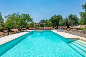 A rectangular swimming pool with a pergola and lounge chairs in a landscaped area with trees. - Casa di Paolo by Rentbeat (Ceglie Messapica)