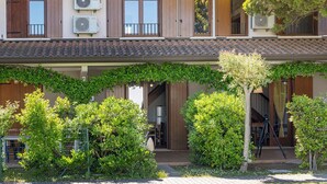 Un immeuble de deux étages doté de climatiseurs, de volets en bois et d’un balcon.