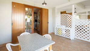 Un espace repas comprenant une table et des chaises, une porte en bois et une cloison blanche.