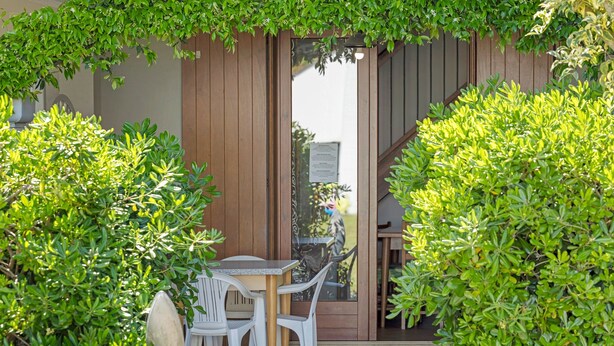 Une terrasse avec une table et des chaises, entourée de verdure.