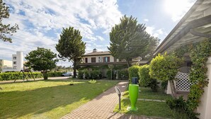 Une cour avec un chemin pavé, un jardinier en forme de bac et un bâtiment doté d’un toit en tuiles.