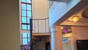 Una escalera con alfombra decorativa y barandilla de metal que da a un balcón.