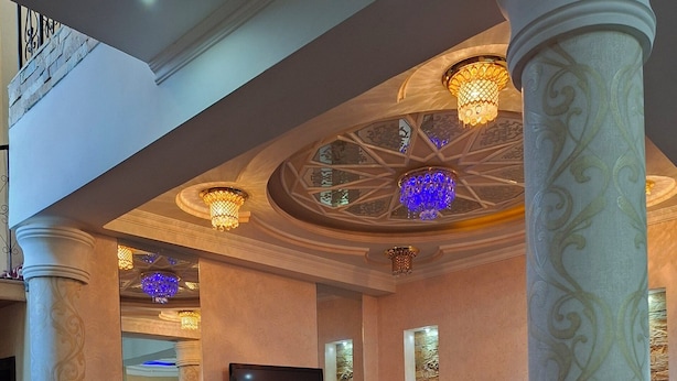 Amplia sala de estar con un televisor de pantalla plana grande, espejos decorativos y un sofá estampado.