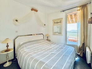 A bedroom with a bed, bedside lamps, a mirror, and a view of a balcony. - Pool & Seaview apartment (La Croix-Valmer)