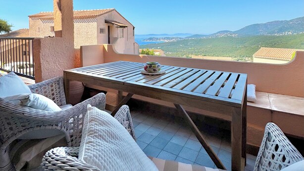 A terrace with wicker furniture, a wooden table, and a striped awning. - Pool & Seaview apartment (La Croix-Valmer)