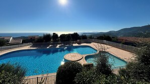 A clear blue sky with a sun shining over a swimming pool surrounded by a fence, with mountains in the background. - Pool & Seaview apartment (La Croix-Valmer)