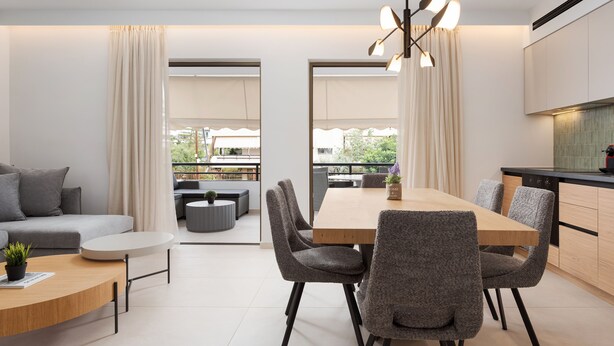 Una sala moderna con sofá, una mesa de centro y una zona de comedor con sillas. Hay una cocina con armarios y una encimera.
