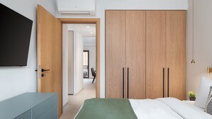 Un dormitorio con cama, armario, televisor y escritorio.