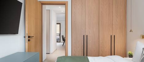 A bedroom with a bed, a wardrobe, a TV, and a desk.