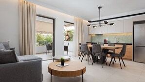 Una sala moderna con un sofá gris, una mesa de centro redonda y un comedor con una mesa de madera y sillas grises.