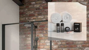 A bathroom with a brick wall, a glass shower enclosure, and a towel rack.