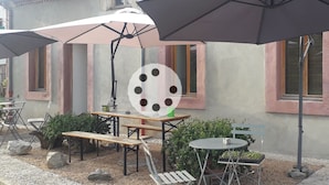 An outdoor seating area with tables and chairs, umbrellas, and a decorative wall.