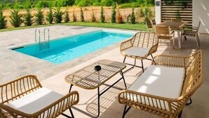 A poolside area with outdoor seating and a view of green hills. - Ioannina Secret Luxury Villas (Vounoplagia)