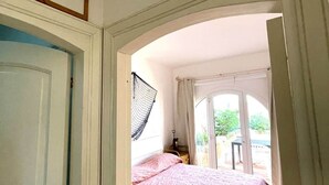 A bedroom with a bed, a window with curtains, and a door leading to another room. - Captain Howard House
 Blackburn Santa Teresa Gallura (Santa Teresa Gallura)