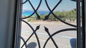 A window with a decorative metal grille and a view of a parking lot and distant landscape. - Captain Howard House
 Blackburn Santa Teresa Gallura (Santa Teresa Gallura)
