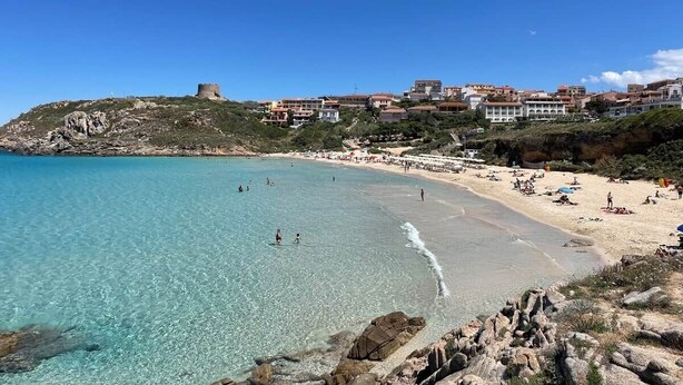 A coastal beach with clear turquoise water, rocky shoreline, and buildings in the background. - Captain Howard House
 Blackburn Santa Teresa Gallura (Santa Teresa Gallura)
