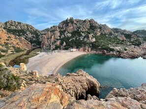 Eine felsige Küste mit einem klaren Strand und ruhigem Wasser.