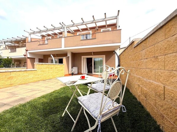 Un patio con mesa y sillas, una pérgola y un muro de ladrillo.