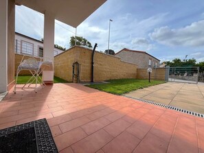 Un espacio al aire libre cubierto con un muro de ladrillo, una silla de metal y una rejilla de desagüe.