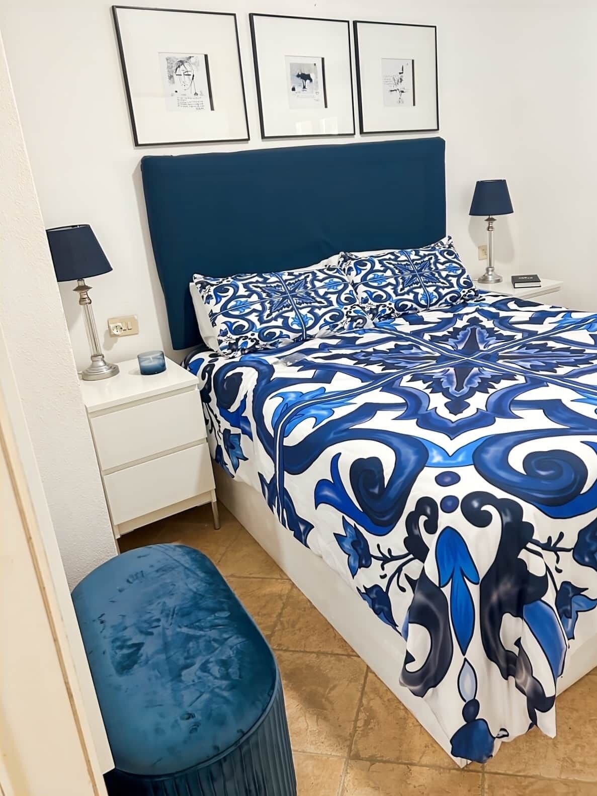 A bedroom with a bed, nightstands, a lamp, and framed pictures on the wall.