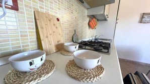 Una cocina con dos tazones blancos sobre individuales tejidos, una estufa a gas y un salpicadero de azulejos.