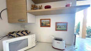 Una cocina con microondas, tostadora y repisas con objetos decorativos.