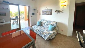 Una sala de estar con un sofá, una mesa de comedor y un televisor.