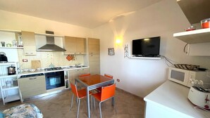 Cocina compacta con comedor, microondas, tostadora y televisor.
