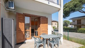 Une terrasse extérieure avec une table et des chaises, une porte en bois et un appareil de climatisation.