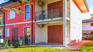 Un bâtiment à deux étages avec une façade rouge, un balcon doté d’une rambarde en métal et une grande porte en bois.