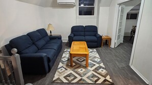 Ein Wohnzimmer mit Deckenventilator, zwei Sofas, einem Holztisch und einem gemusterten Teppich.