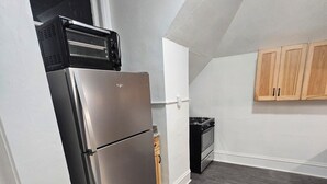Eine kleine Küche mit Kühlschrank, Herd und Holzschränken.