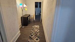 Ein Flur mit einem gemusterten Teppich, einem Schreibtisch mit Stuhl und einem an der Decke befestigten Rauchmelder.