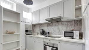 Une cuisine moderne avec des meubles blancs, un four à micro-ondes encastré, une cuisinière et une machine à café.