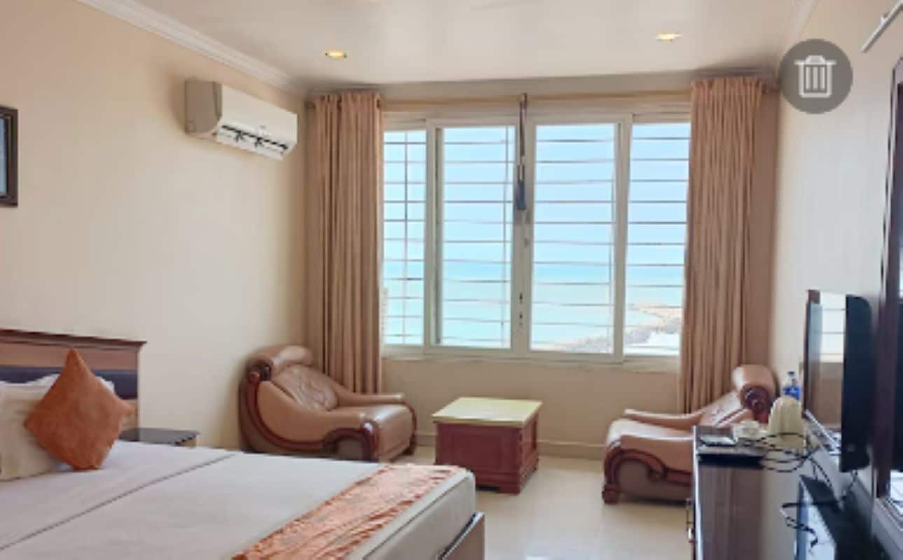 A hotel room with a bed, a desk, a chair, and a window with curtains.