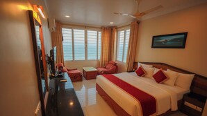 A hotel room with a large bed, a desk, a chair, and a window with curtains.