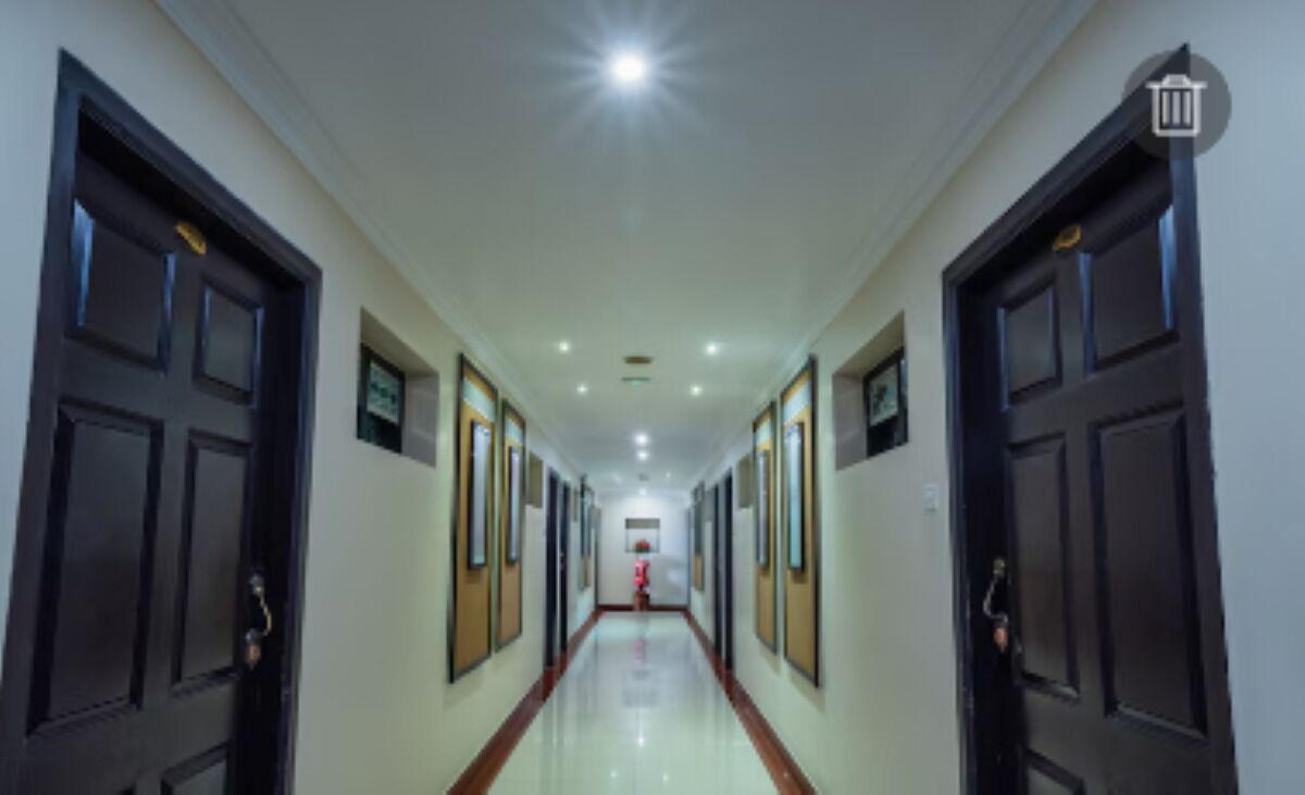 A long, well-lit hallway with dark doors on either side, leading to a room at the end.