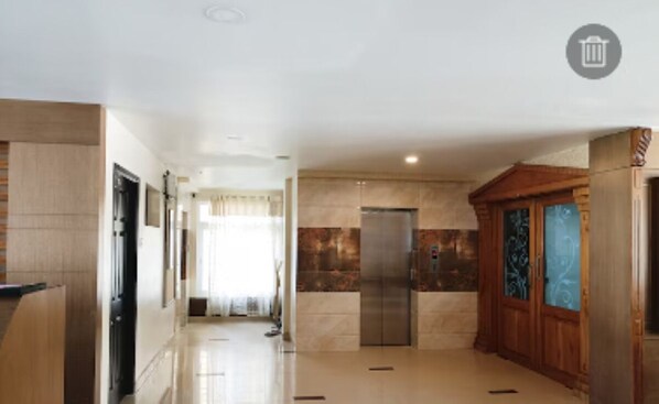 Un interior moderno con un pasillo que conduce a una habitación con una puerta grande y un pequeño ascensor.