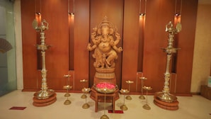 A statue of a deity in a room with wooden paneling and a tiled floor.