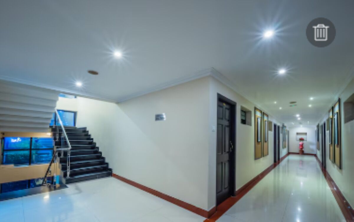 A long, well-lit hallway with a staircase on the left and a door on the right.