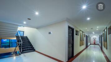 A long, well-lit hallway with a staircase on the left and a door on the right.