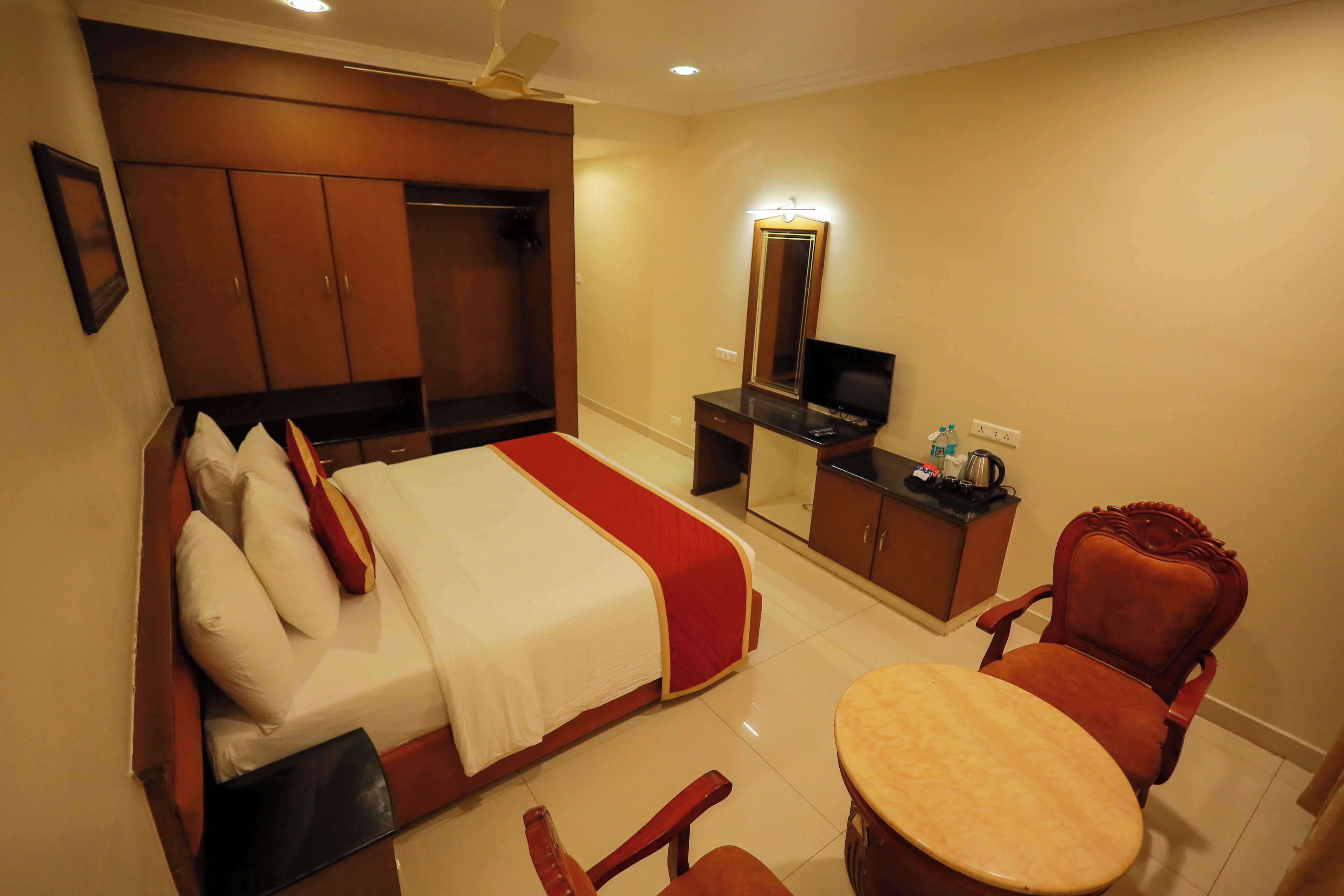 Une chambre d’hôtel comprenant un lit, un bureau, une chaise, une télévision et une armoire.