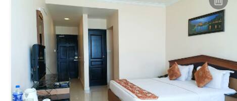 A hotel room with a bed, a television, a desk, and a nightstand.