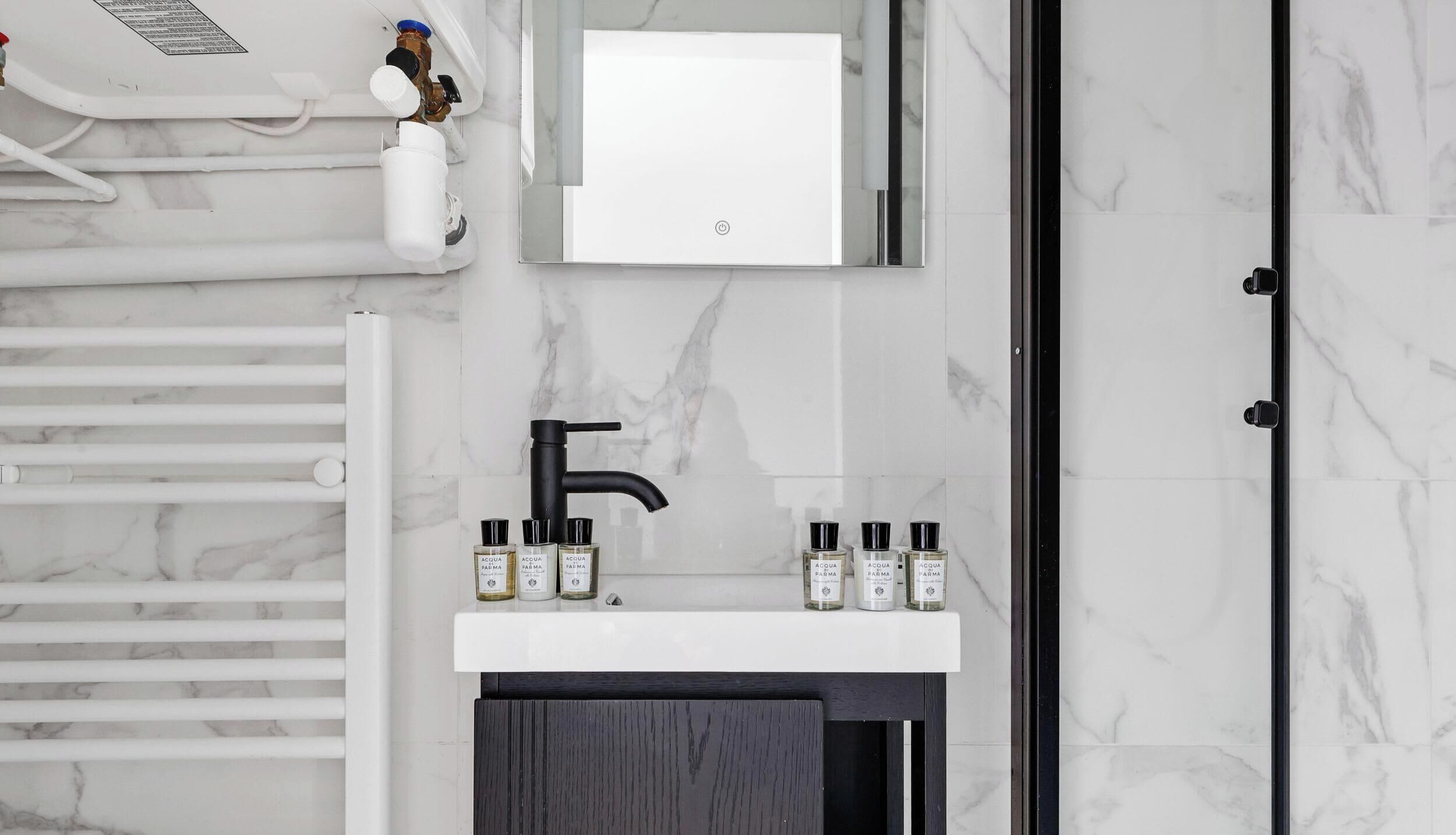Une salle de bain avec un lavabo blanc, un robinet noir et des carreaux de marbre.