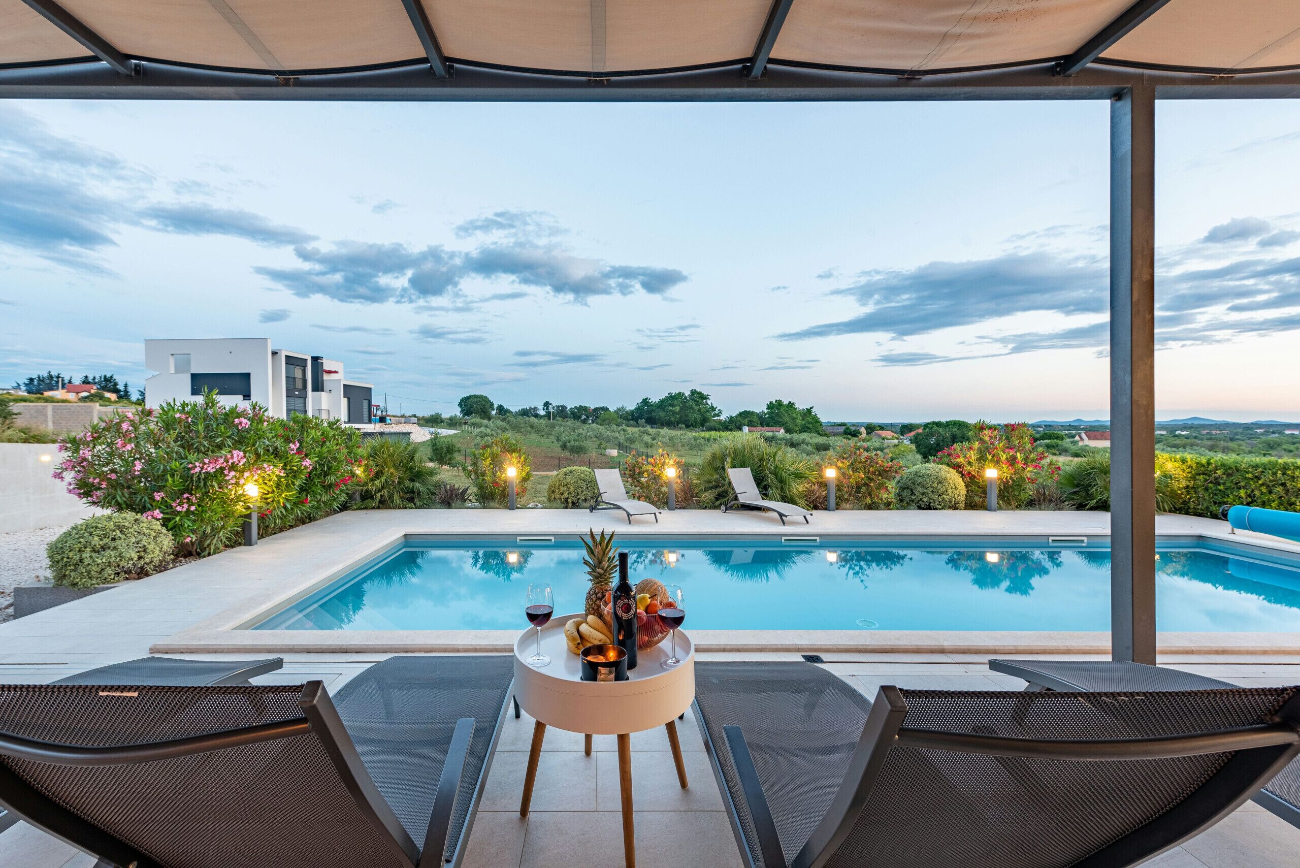 Zona junto a la piscina con una mesa para dos, una piscina y vistas del paisaje.