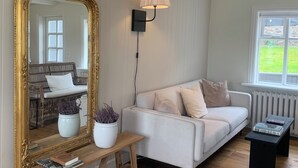 A living room with a large ornate mirror, a white sofa, a wooden coffee table, and a floor lamp. - Aðalstræti - Historic Luxury Villa (Akureyri)