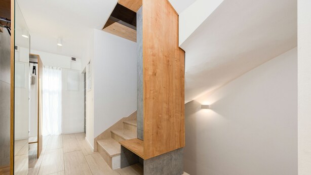 A modern staircase with wooden and concrete elements, leading to a room with a white door and a mirror. - Villa Descansa Zadarvillas (Nin)