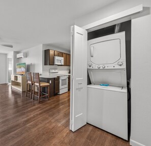 A compact kitchen with a microwave, stove, and a built-in washer-dryer unit. - 2BR ¼ mi to Kam 1 Beach, Pool, Hot Tub, Gym, BBQ (Kihei)