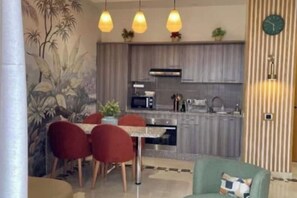 Une cuisine moderne équipée d’un four à micro-ondes, d’une cuisinière et d’un évier. On y trouve également un coin repas avec des chaises rouges et une table.