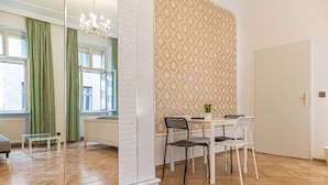 Une pièce comprenant une table à manger, deux chaises, une plante en pot et un miroir.